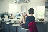 Mixed Race Boy Sitting In Kitchen Listening To Cell Phone Stock Photos