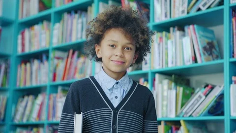 Mixed race boy smiling at camera in school library Stock Footage 108750074