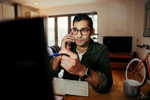 Mixed race business man pointing to laptop screen while on the telephone with Stock Photos