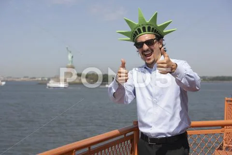Mixed race businessman on ferry wearing statue of liberty hat Stock Photos