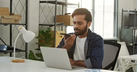 Mixed race businessman using voice assistant on smartphone while working. Stock Footage 335851715