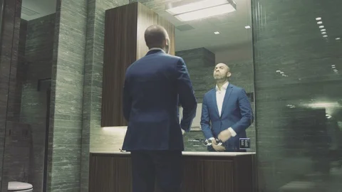 Mixed race CEO checks himself in mirror then puts on glasses before meeting WIDE Stock Footage 105010983