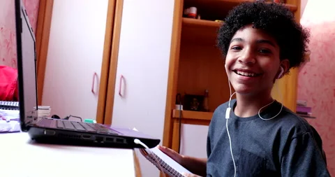 Mixed race child smiling at camera in front of computer desk, kid doing homew Stock Footage 144418801