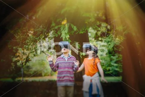 Mixed race children using virtual reality goggles outdoors Stock Photos