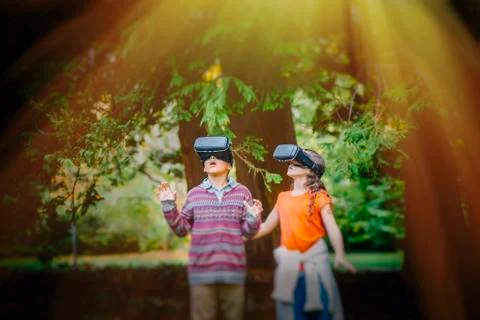 Mixed race children using virtual reality goggles outdoors Stock Photos