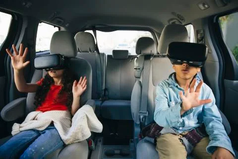 Mixed race children using virtual reality goggles in car Stock Photos