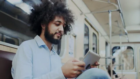 Mixed race Cool Guy with Dark Skin Using Tablet PC in Subway or Metropolitan Stock Footage 136069904