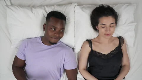 Mixed-race couple lying in bed and making fist bump gesture. Top view. Stock Footage 136574519