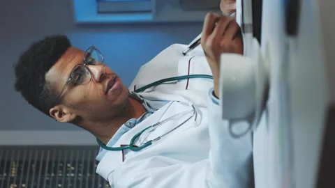 Mixed-race doctor making notes and talking by video call on computer Stock Footage 131533850