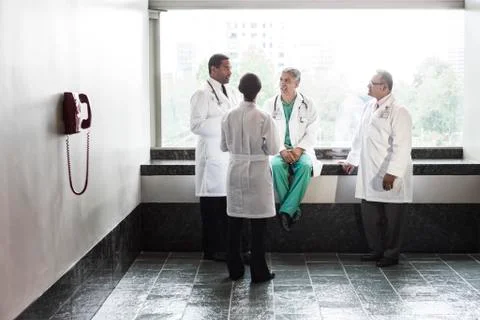 Mixed race doctors conferring in a hospital hallway. Stock Photos