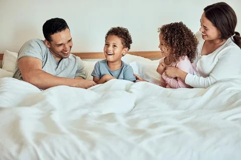 Mixed race family lying in bed, smiling and playing. Latino parents having fun Stock Photos