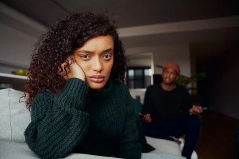Mixed race female angry with black boyfriend while fighting on the sofa in Stock Photos