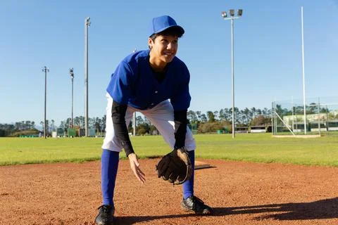 Mixed race female baseball pitcher standing on sunny baseball field smiling Stock Photos