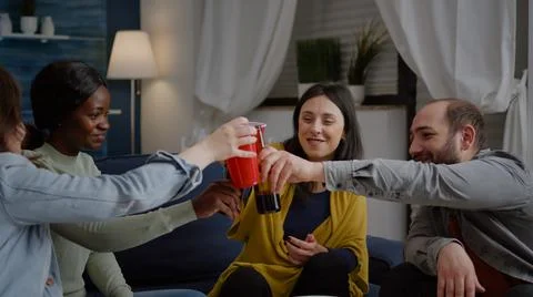 Mixed race friends chatting during night party while sitting on sofa Foto stock