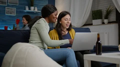 Mixed race friends talking while looking at funny video series on laptop Stockfoto's
