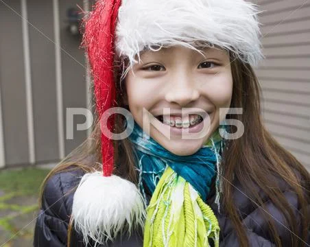 Mixed race girl in braces wearing Santa hat Stock Photos