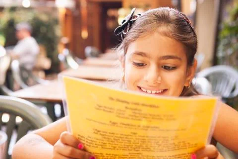 Mixed race girl reading menu in restaurant Stock Photos