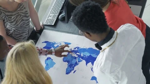 Mixed-race group examining the world map Stock Footage 73850277