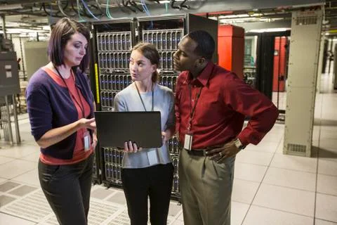 Mixed race group of technicians doing diagnostic tests on servers in a large Stockfoto's