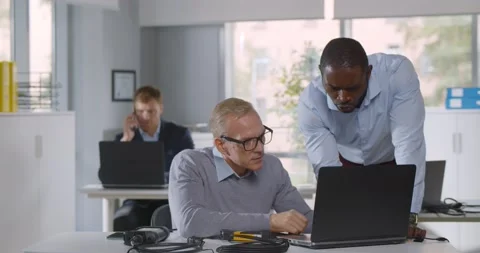 Mixed-race it-technician fix laptop for mature businessman in office Stock Footage 162028912