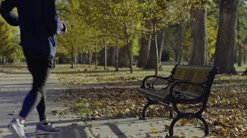 Mixed Race Jogger Uses Bench To Stretch, Gets Text And Sits Down, Jogs Off Stock Footage 69930406