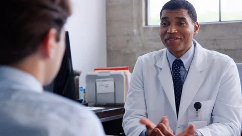 Mixed race male doctor speaking to young patient Stock Footage