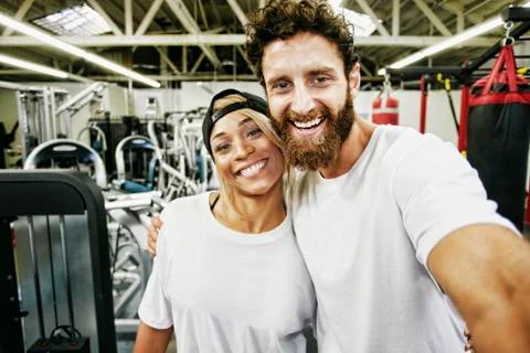 Mixed Race man couple posing for cell phone selfie in gymnasium Stock Photos