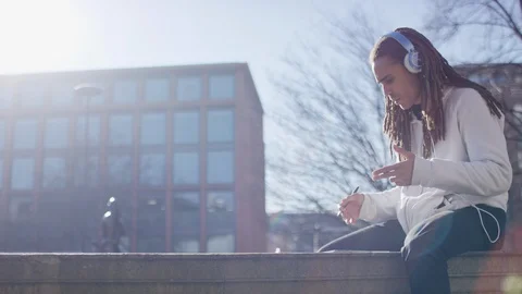 Mixed race man with dreadlocks writing lyrics as he listens to music Video stock 103804283