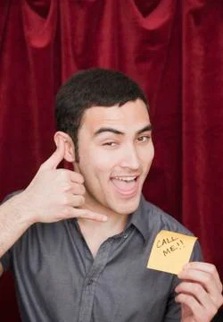 Mixed race man holding call me sticky note and gesturing Stock Photos