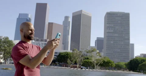 Mixed race man puts away phone and looks at Downtown LA 4K Stock Footage 64657912