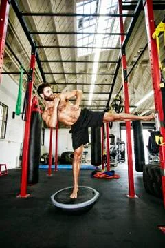Mixed Race man standing on balance trainer in gymnasium Stock Photos