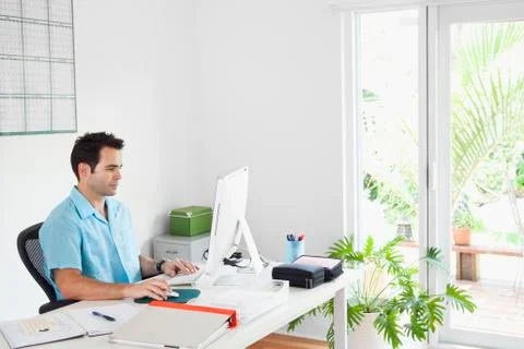 Mixed Race man using computer in home office 库存照片