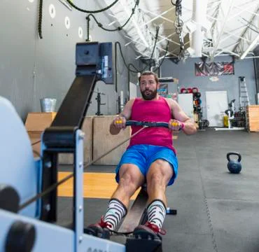 Mixed Race man using rowing machine in gymnasium Foto stock