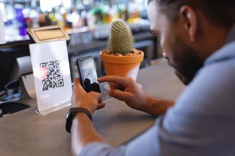 Mixed race man using smartphone and reading qr code in cafe Stockfoto's