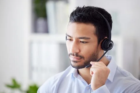 A mixed race man working in a call center. Operator using a wireless headset Stock Photos
