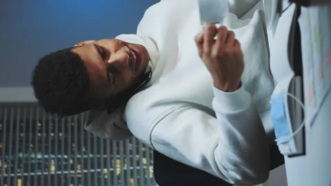 Mixed-race man working on computer, speaking by smartphone and drinking a cup of Stock Footage 131532640