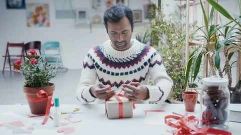 Mixed race man wrapping or preparing birthday, valentines day, Christmas present Stock Footage 101041059