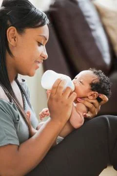 Mixed race mother feeding bottle to newborn baby Stock Photos