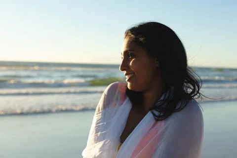 Mixed race patriotic woman on the beach wearing shawl looking toward sea Stock Photos