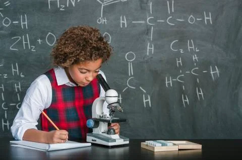 Mixed race student using microscope in science class Foto stock