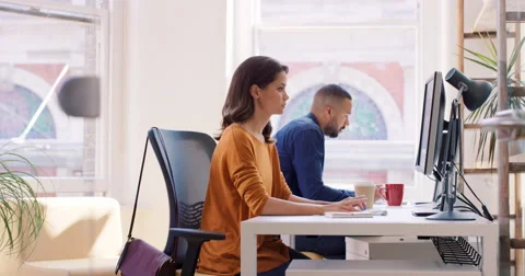 Mixed race team of young business people working in open plan office desk rows Stock Footage