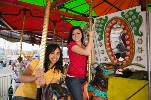 Mixed Race teenaged girls on carousel horse Stock Photos