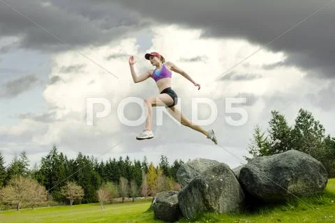 Mixed race teenager jumping from rock Stock Photos