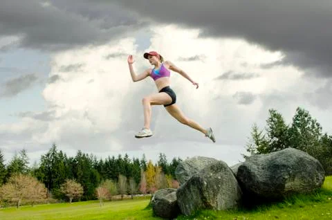 Mixed race teenager jumping from rock Stock Photos