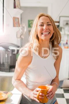 Mixed race woman drinking coffee in kitchen Stock Photos