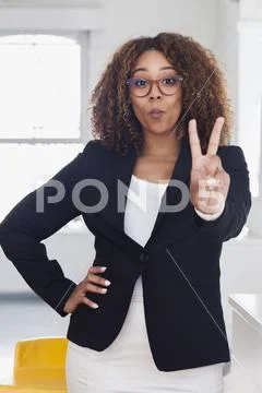Mixed race woman gesturing peace in gallery Stock Photos