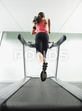 Mixed race woman running on treadmill Stock Photos