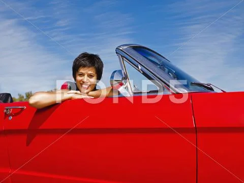 Mixed race woman sitting in red convertible Stock Photos