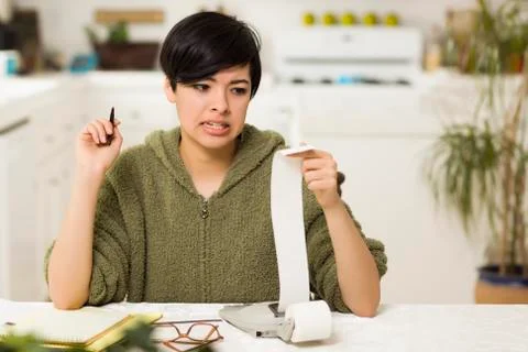 Mixed Race Young Female Agonizing Over Financial Calculations in Her Kitchen. Stock Photos
