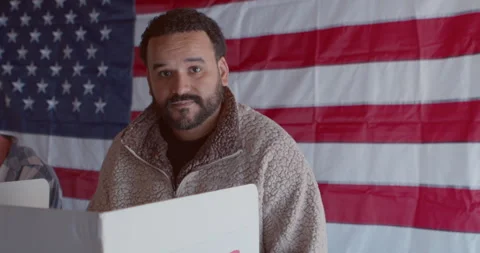 Mixed race young man voting at a polling station with a serious expression Stock Footage 274930886